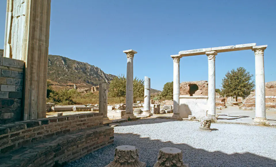 Re-erected columns and a lintel in the Church of Mary, with low ruins and hills behind