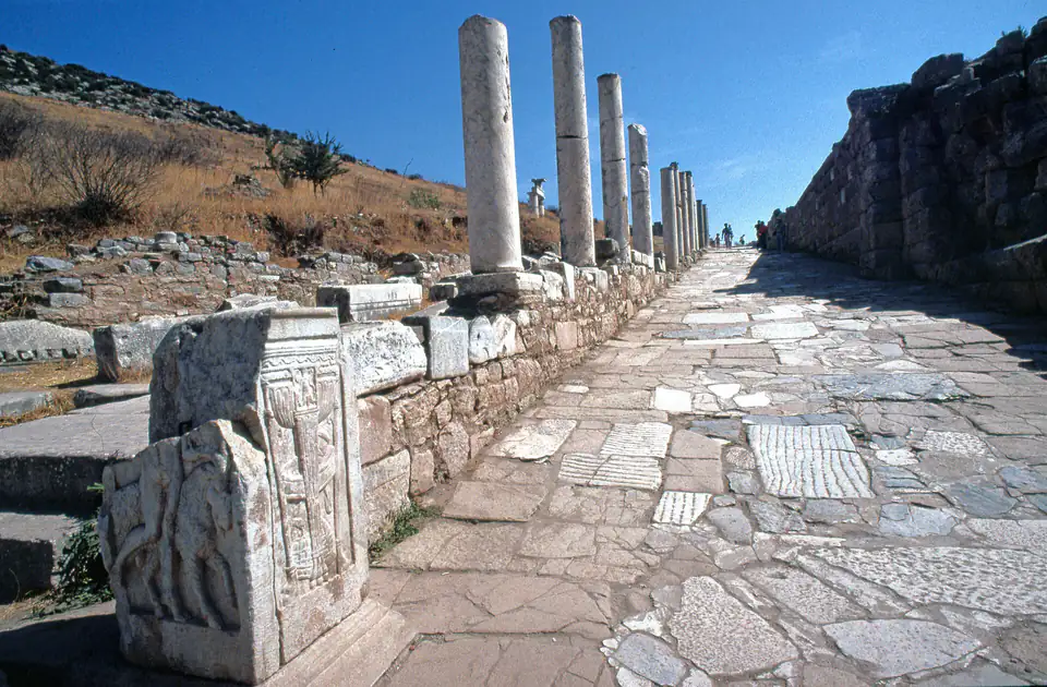 Curetes Street climbing between re-erected columns and carved blocks under a deep blue sky