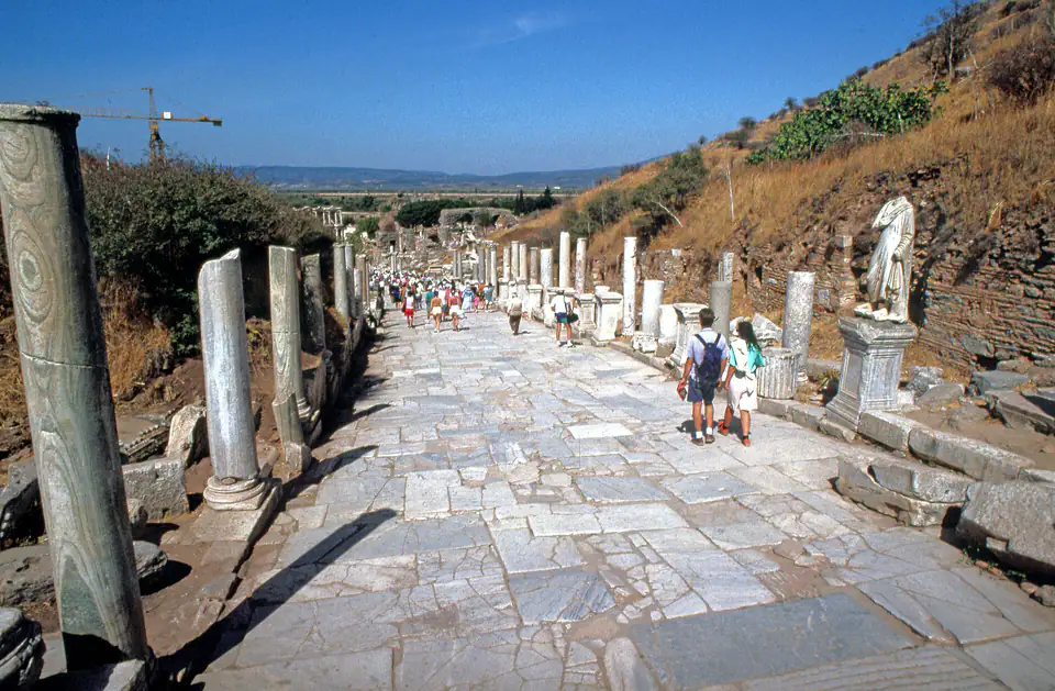 Looking down Curetes Street past columns and statue bases, with visitors