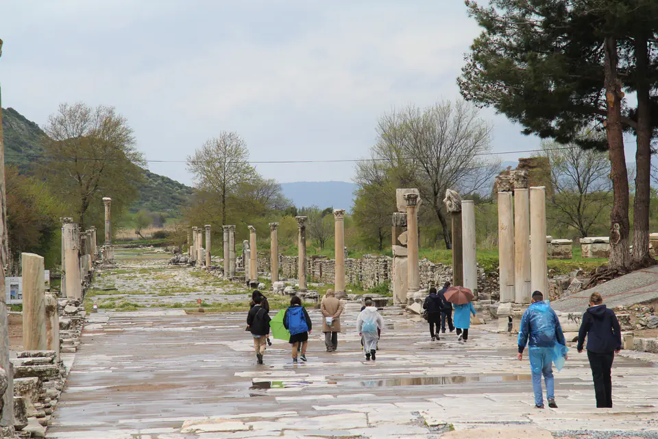 Visitors walk along a broad marble street between rows of columns