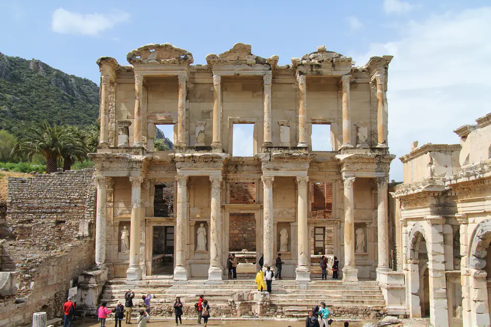 The full façade of the Library of Celsus with visitors on the forecourt and the Mazaeus-Mithridates Gate at right